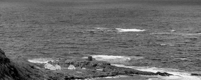 A group of cottages are seen on a dramatic coastline