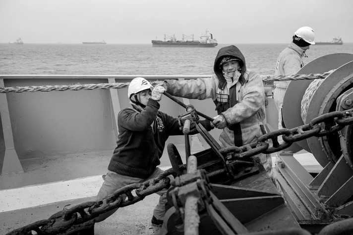 Two crew members on board a vessel work on the deck