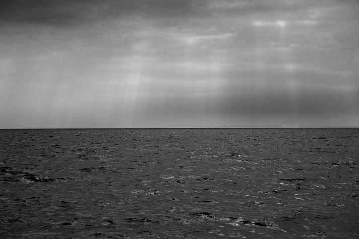 A calm seascape under a dramatic, dark sky