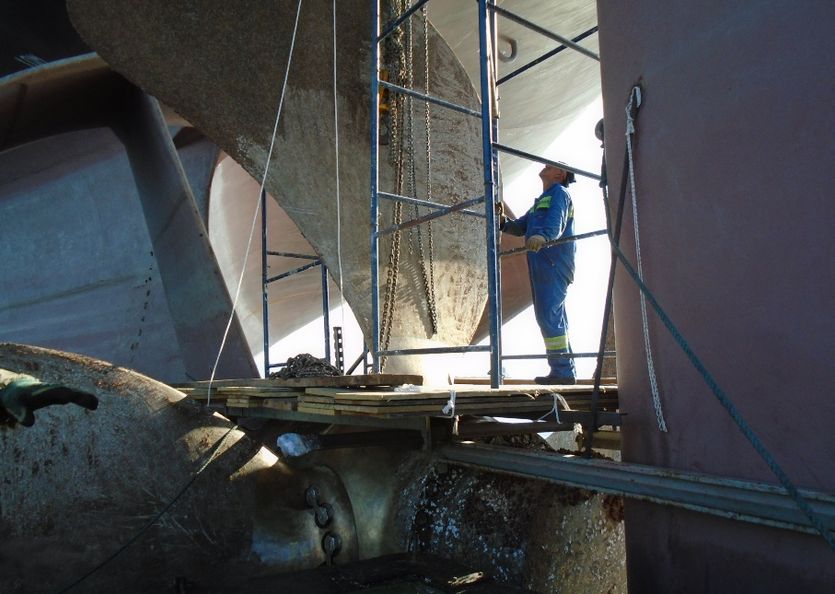 A surveyor inspects a propeller in a dry dock
