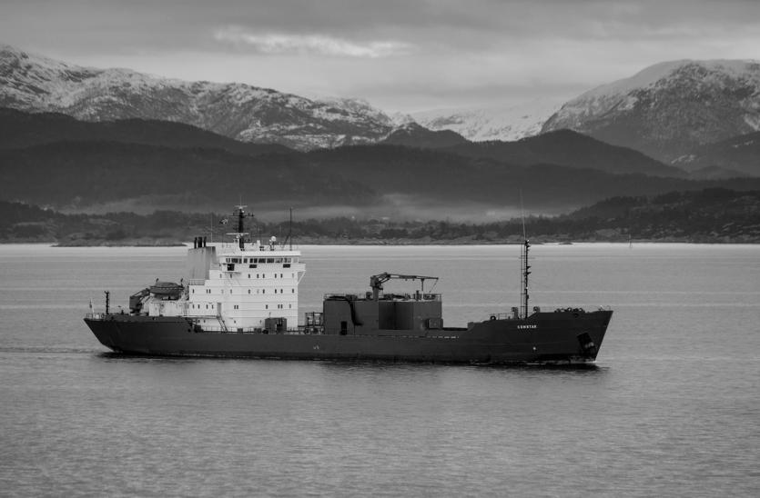 A vessel against a mountainous coastline