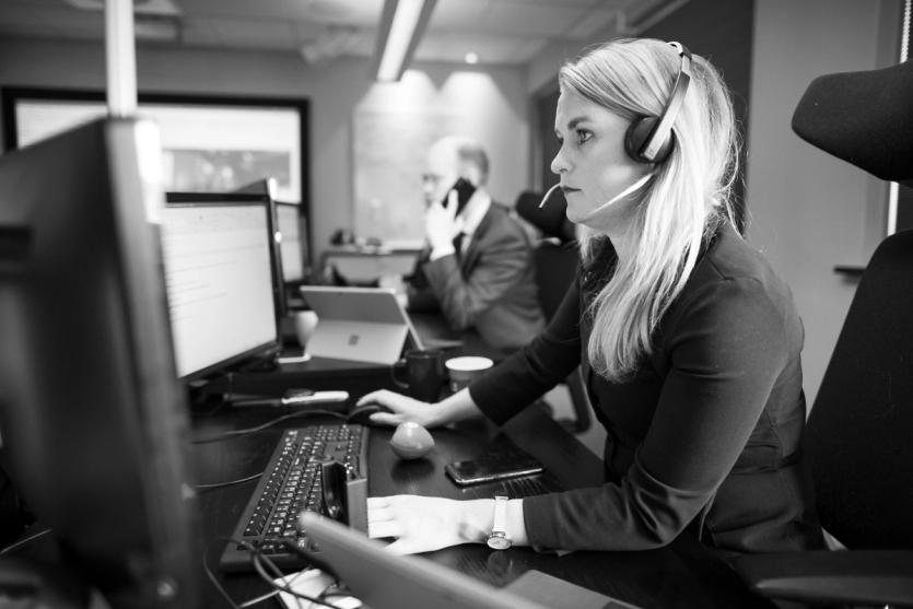 A woman works at her computer with a headset in an operations room