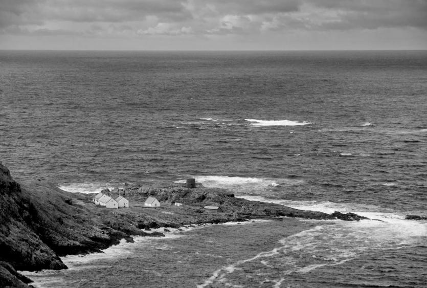 A group of cottages are seen on a dramatic coastline