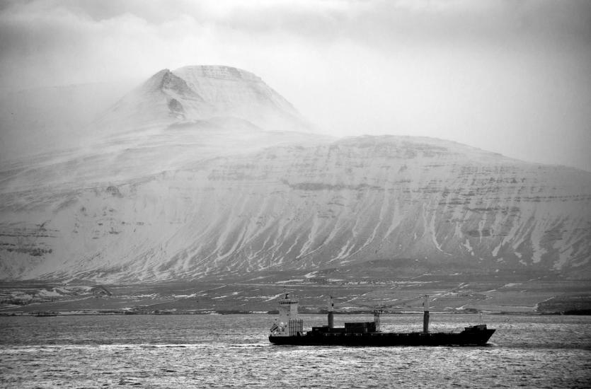 A tanker vessel is seen against a huge mountain by the coast