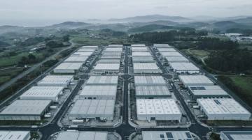 Polígono industrial de naves rectangulares alineadas con las cubiertas claras, visto desde arriba