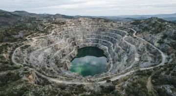 Cantera abandonada con terrazas escalonadas y una laguna verde en el fondo