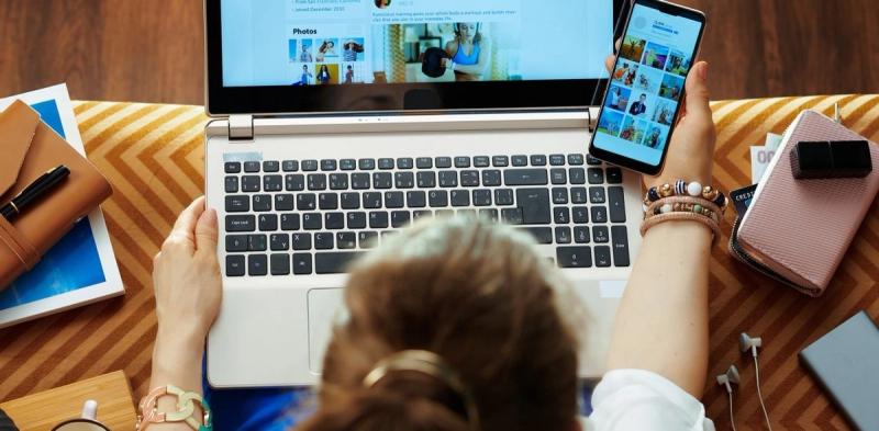 Person reading phone while on the laptop.