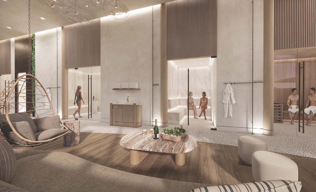 The lounge at Värra, looking through to a lit sauna where two people sit talking, with a hanging chair, a stone table set with sparkling wine, and robes on a rail.