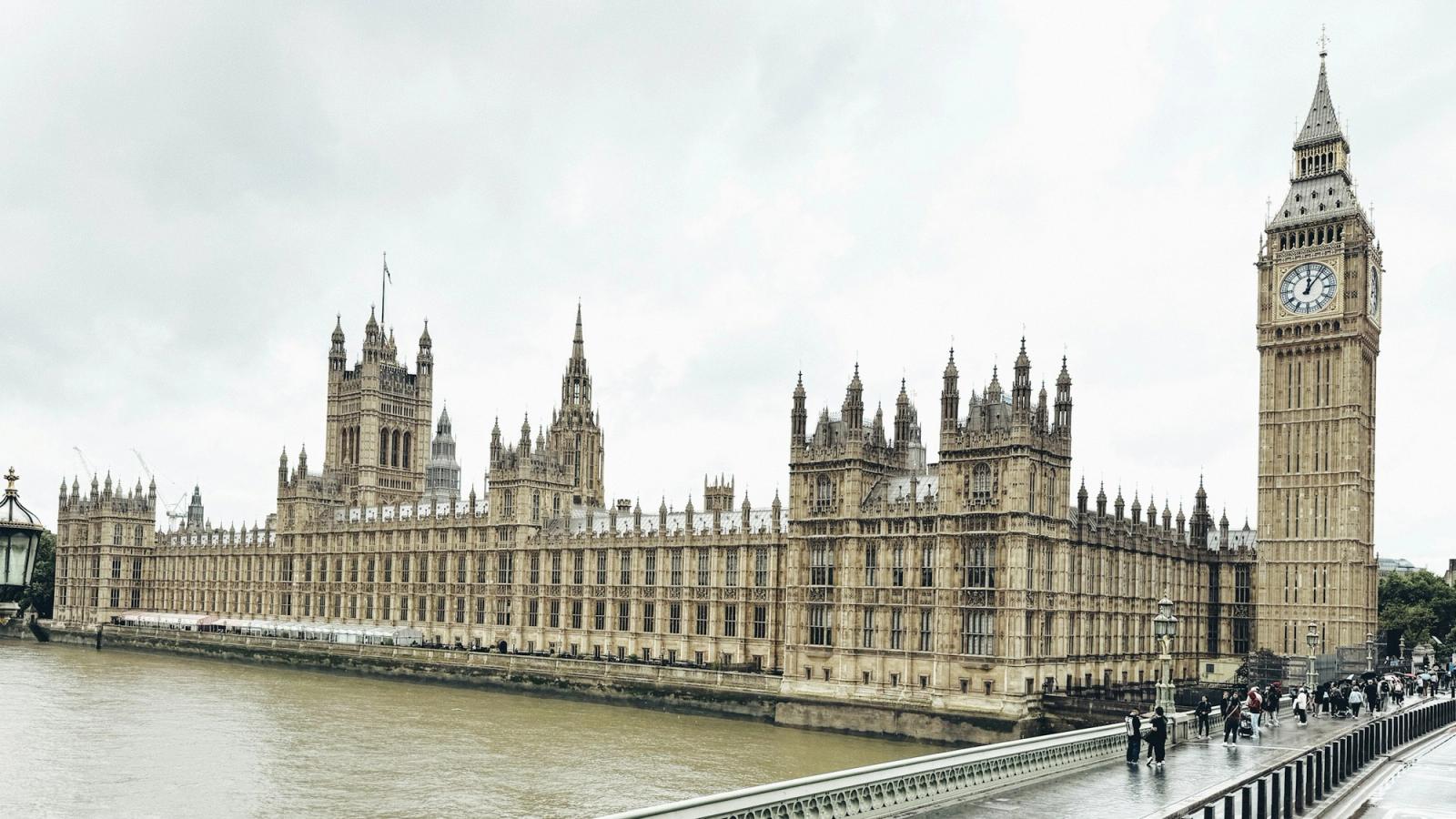 The Houses of Parliament and Big Ben in London, with people crossing Westminster Bridge