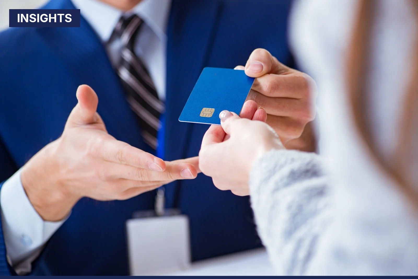 Bank employee in a blue suit hands a blue credit card to a customer