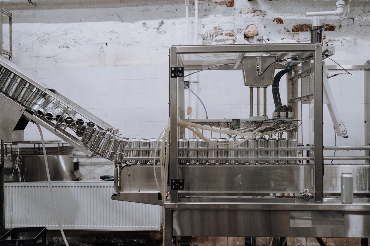 Metal cans move along a conveyor through an industrial filling machine.