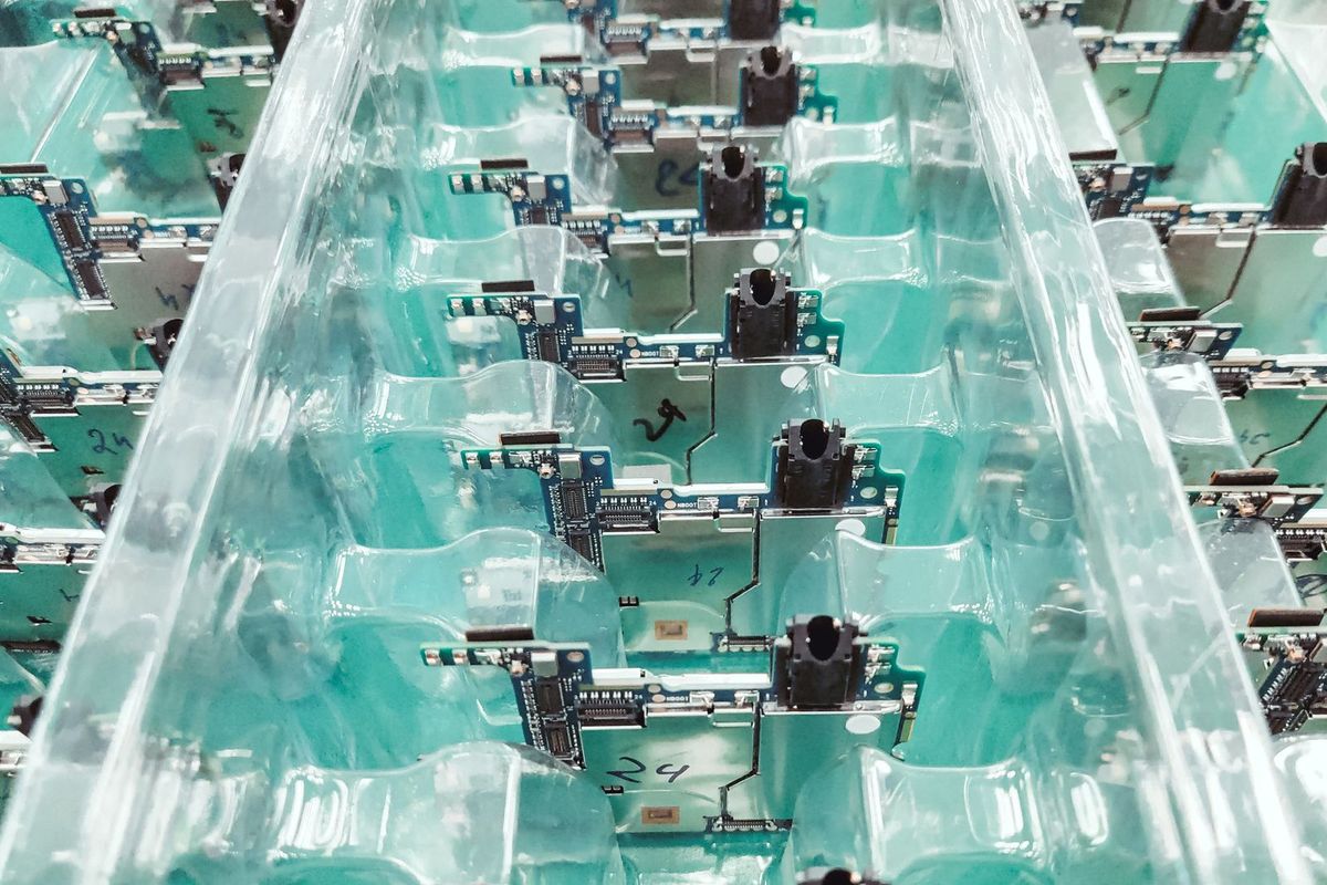 Rows of electronic circuit boards arranged upright in clear plastic packaging trays.