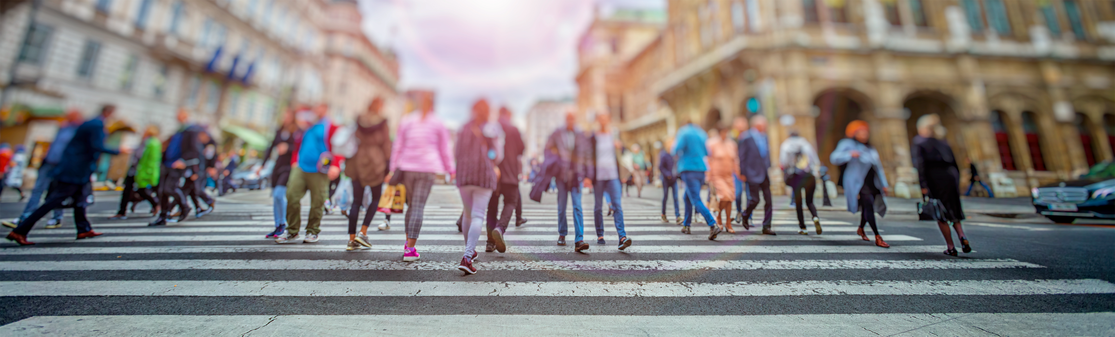 People walking across a pedestrian crossing in a busy urban environment.