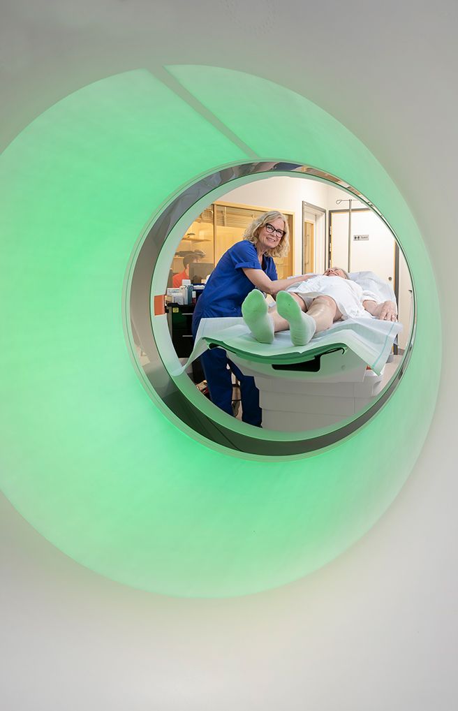 Radiology staff preparing a patient for a CT scan inside the imaging machine.