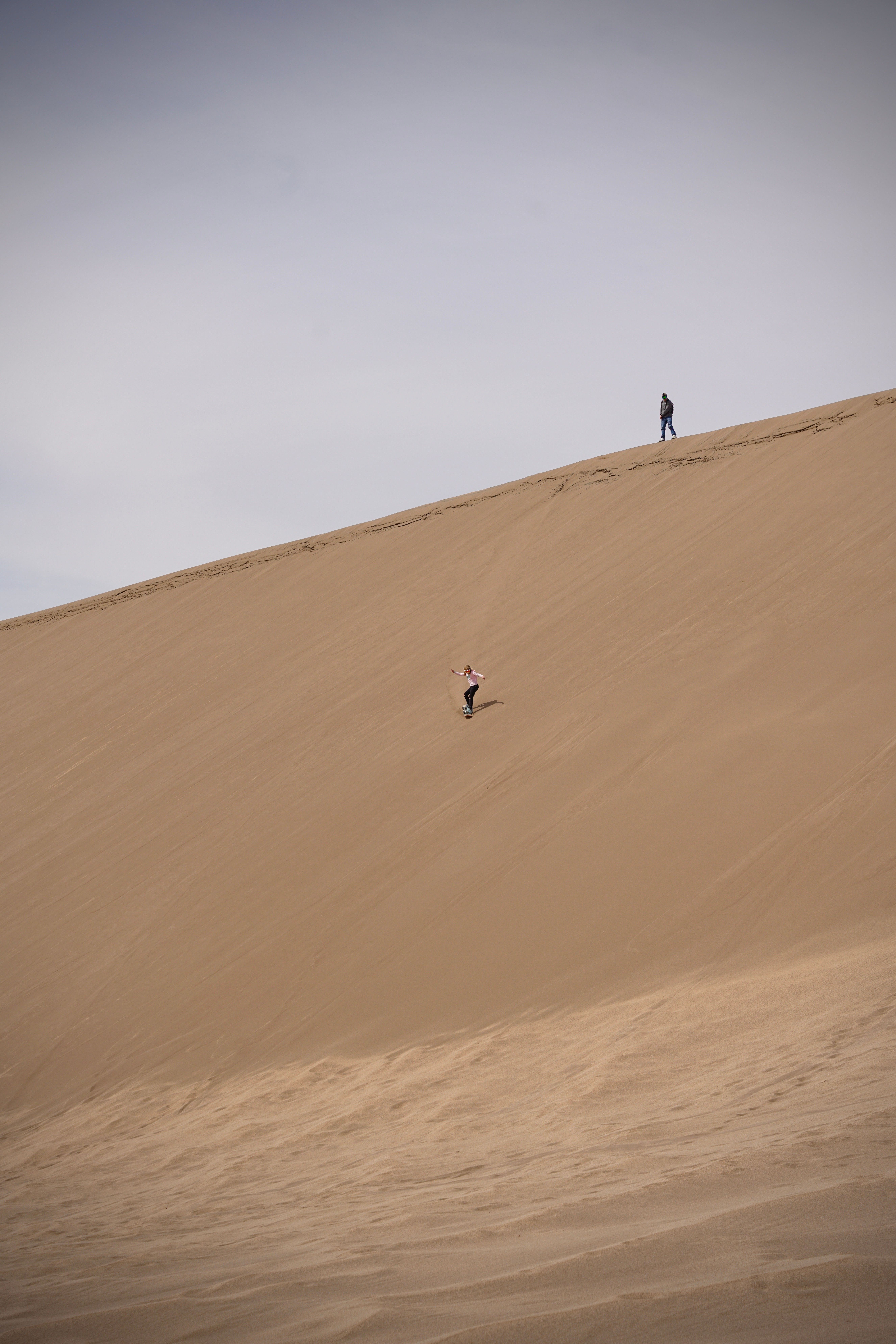 two people skating down sand