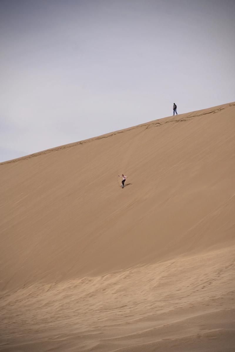 two people skating down sand