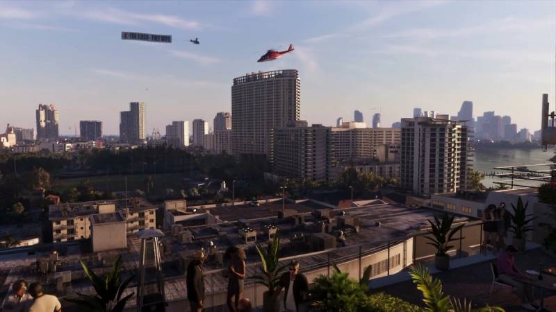 A red helicopter and a banner plane fly over the Vice City skyline, seen from a rooftop bar at sunset.
