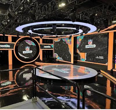 Estudio tecnológico terminado con iluminación circular, muros multimedia y piso negro pulido