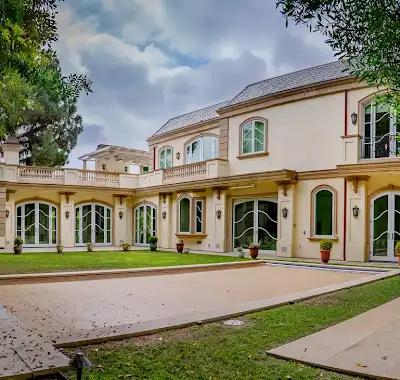 Residencia terminada con estuco claro, ventanas arqueadas, terrazas y jardín