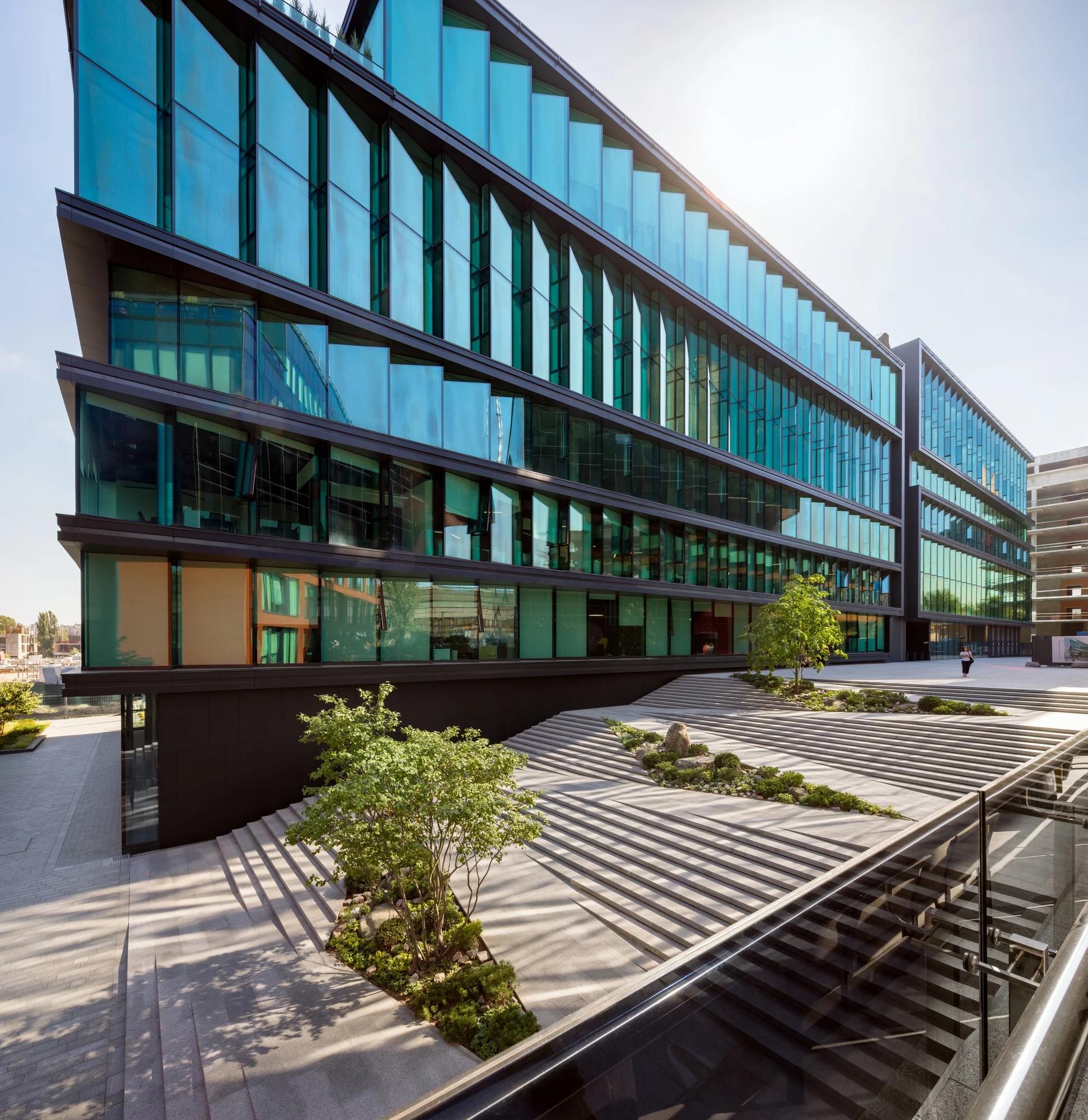 Campus de oficinas contemporáneo con fachadas de vidrio y áreas peatonales ajardinadas