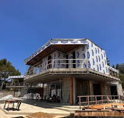 Casa de varios niveles en construcción con barrera climática y andamios