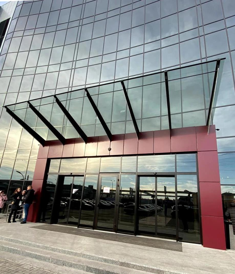 Acceso comercial con marquesina de vidrio en voladizo y soportes de acero