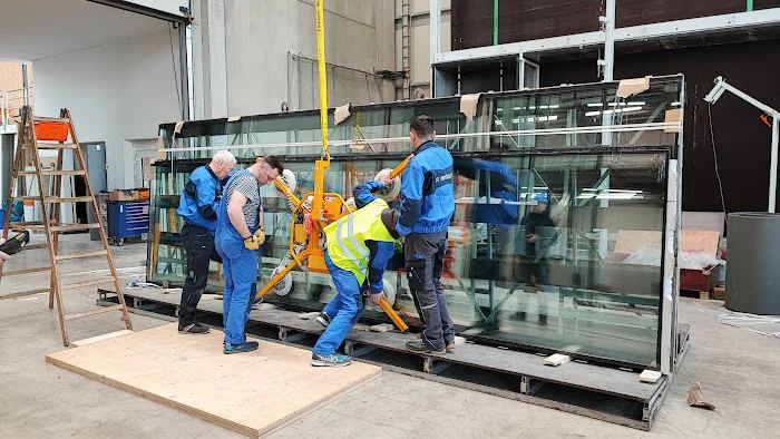 Crew installing large reflective glass panels with mobile scaffolding