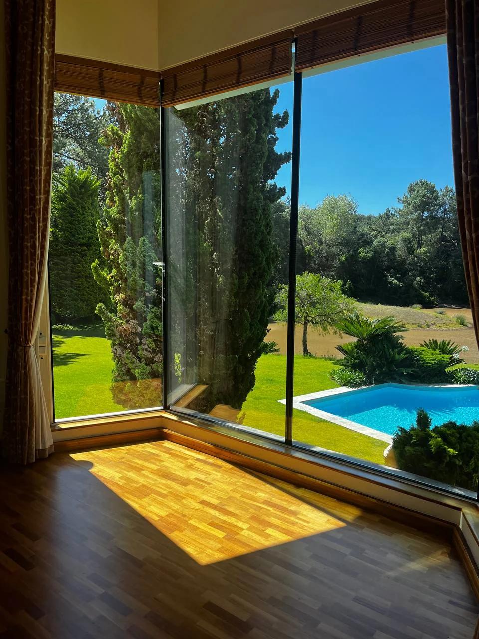 Residential glazed corner with wood trim overlooking a pool and landscaped grounds