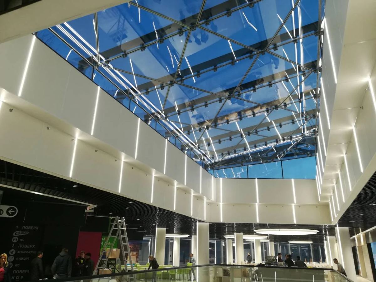 Commercial interior beneath a large structural glass skylight and coordinated steel framing