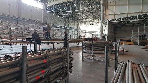 Construction crew assembling steel elements inside a large industrial building