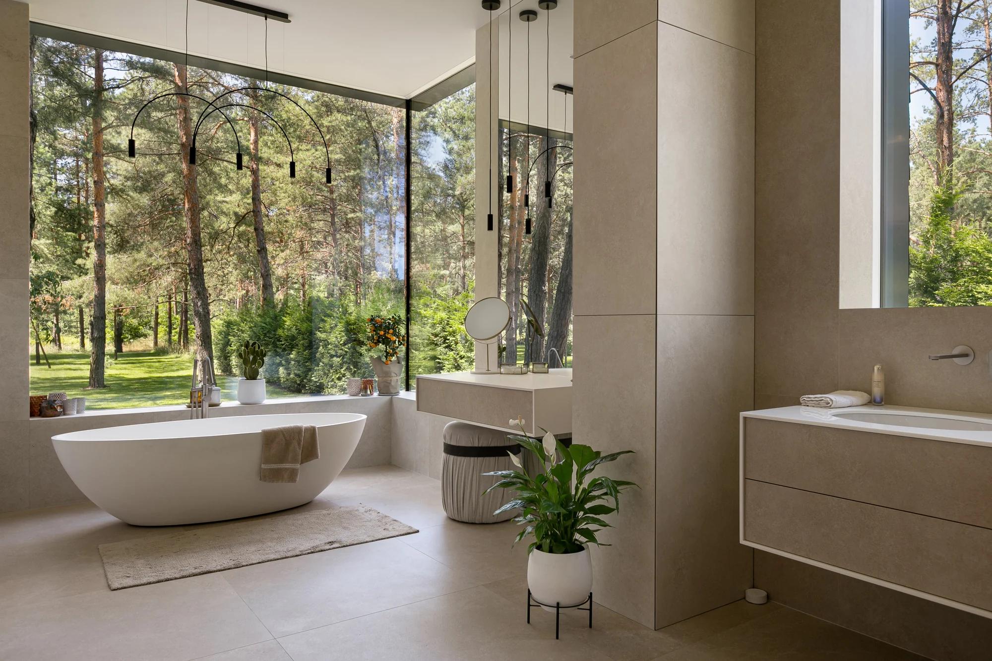Completed luxury residential bathroom with freestanding tub, stone finishes, and garden views