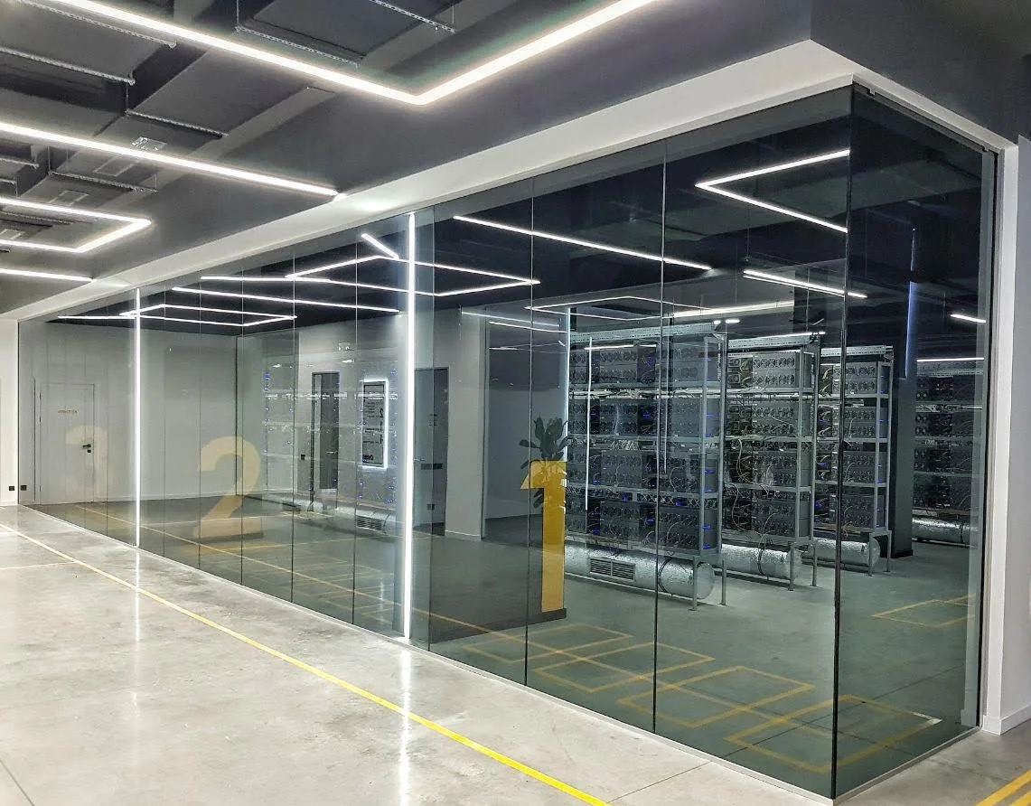 Finished glass-enclosed technical data hall with equipment racks and linear lighting