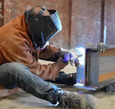 Especialista soldando un componente estructural de acero en obra