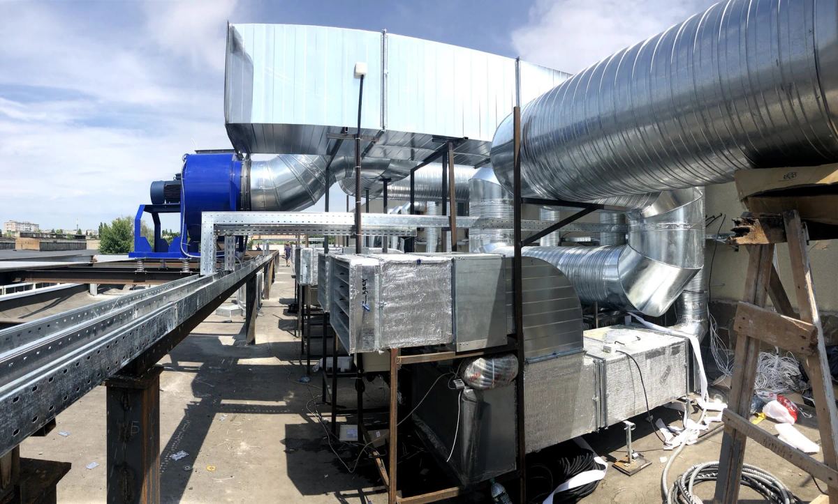Industrial rooftop ventilation system with large ducts, fans, supports, and cable tray