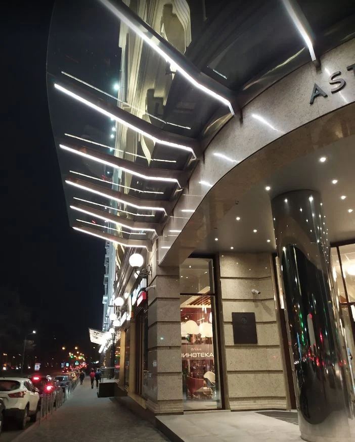 Commercial interior with curved ceiling finishes, reflective surfaces, and integrated linear lighting