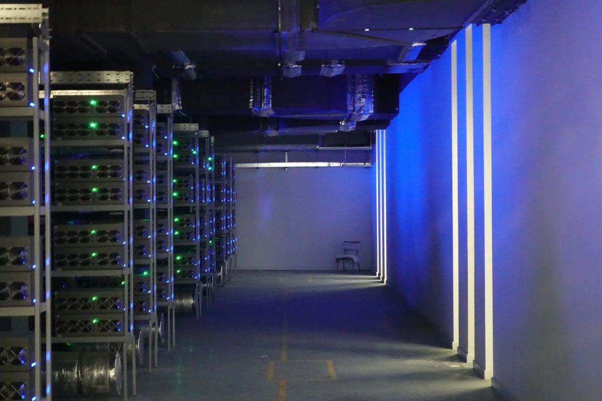 Technical equipment rows with overhead ventilation and blue illuminated access corridor