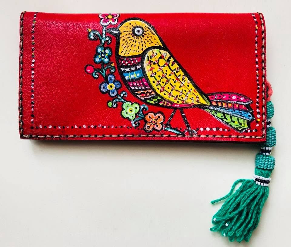 A red wallet decorated with a colourful bird and a green tassel.