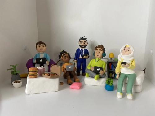 Five handmade clay characters with laptops, tablets and phones, surrounded by tiny food, plants, cushions, a bookshelf and a bicycle.
