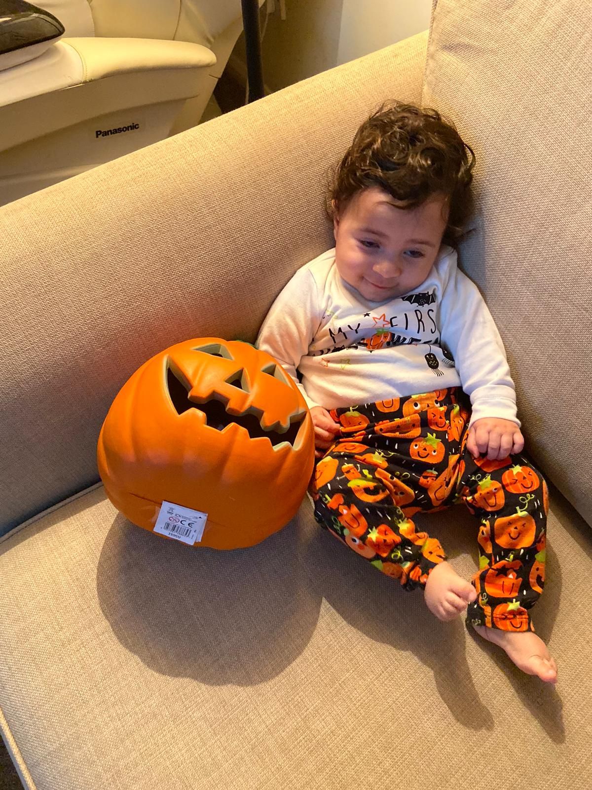 Zain as a baby, sitting beside an orange pumpkin bucket.