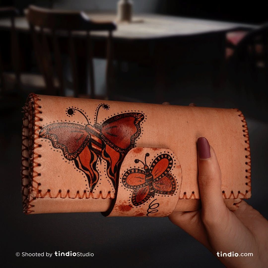 A leather wallet decorated with a painted butterfly and floral patterns.