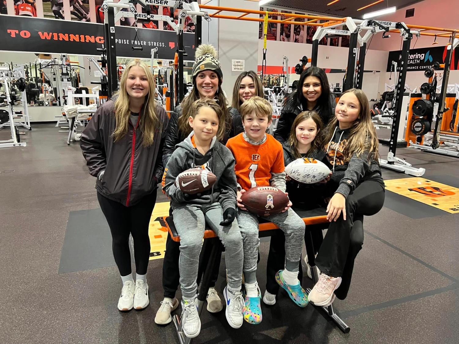 2022 winner Brigida Loucks and family in the Bengals gym holding signed footballs