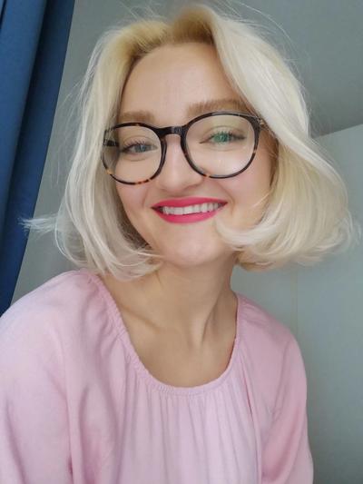 a woman wearing glasses and a pink shirt is smiling for the camera .