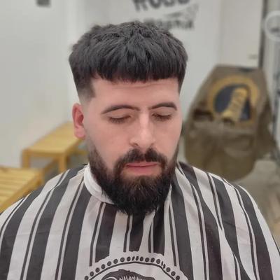 un hombre con barba se está cortando el pelo en una barbería .