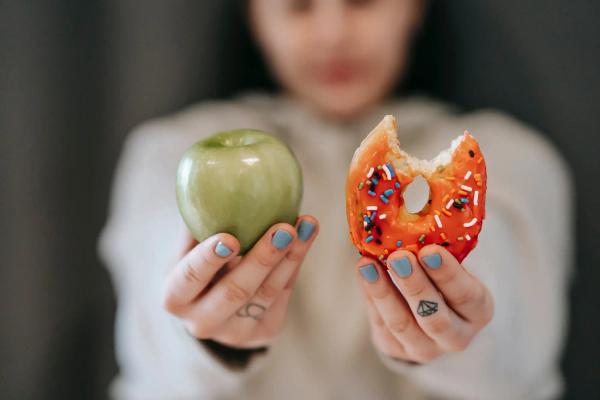 Woman holding apple and donut