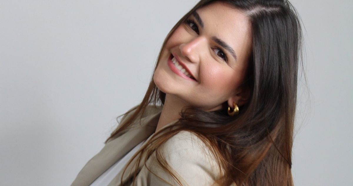 een vrouw met lang haar draagt een blazer en glimlacht .