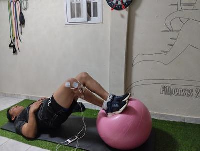 un hombre está tumbado en una colchoneta junto a una pelota de ejercicios rosa .