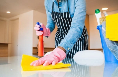 a woman wearing pink gloves is cleaning a table