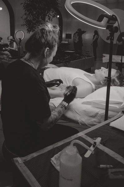 una foto en blanco y negro de una mujer haciéndose un tatuaje