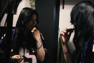 una mujer se está pintando los labios delante de un espejo .
