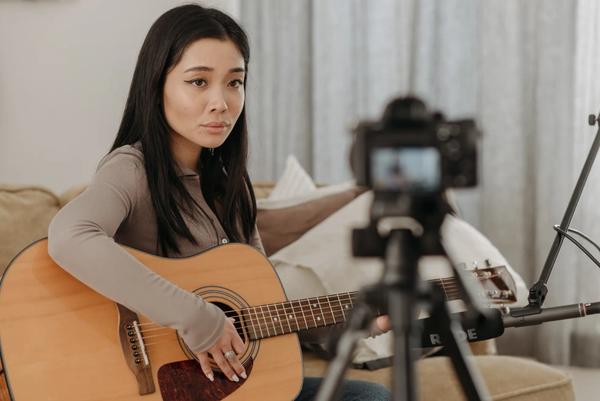Woman playing guitar in front of camera